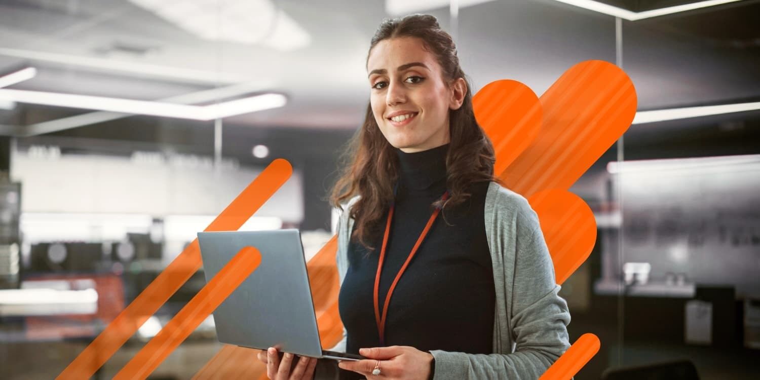 One person, smiling, while holding an open laptop in their hands.